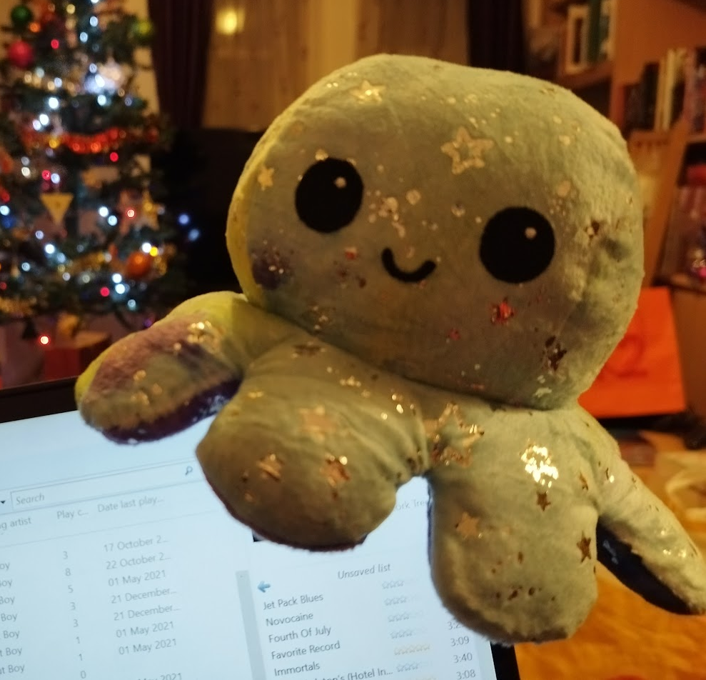galaxy octopus 2 A pale blue star patterned octopus plush with a happy expression perches on the corner of a laptop, with a Christmas tree visible in the background.